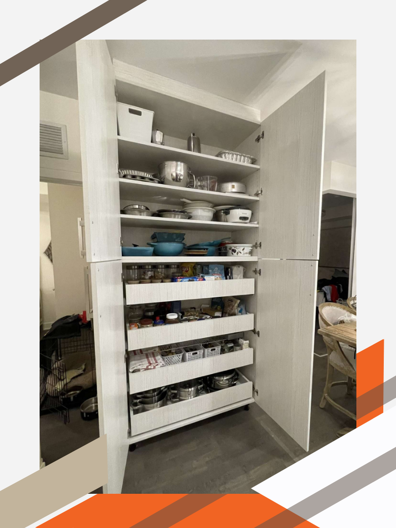 Two square pantry cabinets are stacked on top of each other and mounted to the wall. The cabinet doors are open to reveal the bottom cabinet holds 4 open drawers. The top cabinet holds 4 rows of shelving.